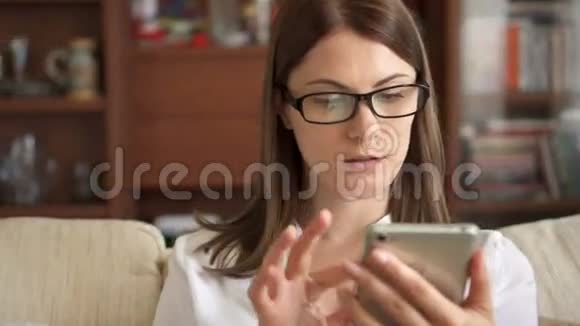 在家里用手机发短信的女人年轻漂亮的女性智能手机专业人士视频的预览图