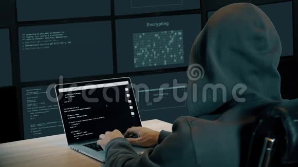 黑客在监控室的笔记本电脑上打字戴帽子的人坐在桌子旁黑客肩上的笔记本电脑屏幕视频的预览图