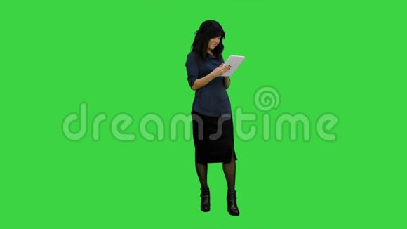 年轻的亚洲女性使用数字平板电脑在绿色屏幕上微笑Chroma键视频的预览图