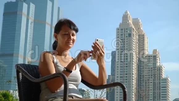 在摩天大楼背景下使用电话的严肃女人视频的预览图
