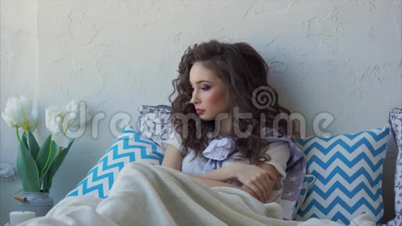 一个刚刚醒来的年轻女子躺在床上靠在枕头上视频的预览图