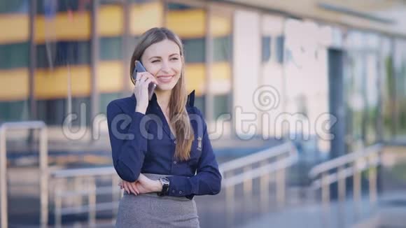 一位忙碌的商务女士正在工作休息期间用手机聊天这位女士正在和附近的一位同事聊天视频的预览图