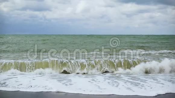一股巨浪缓慢地拍打着卵石滩视频的预览图
