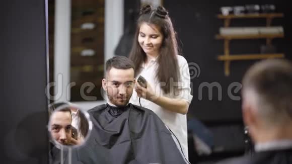 一位漂亮的发型师为沙龙的幸运访客做了一个发型一位女士用修剪器剪了头发视频的预览图