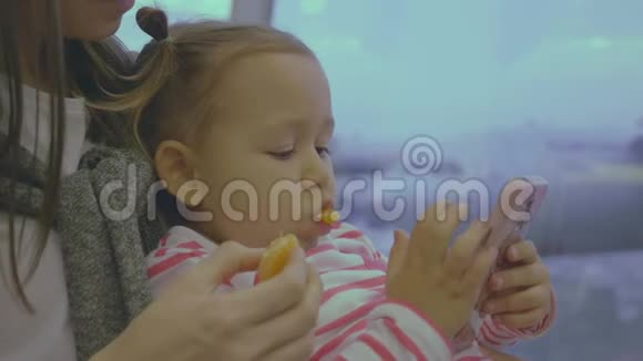 母亲在机场慢动作地用橘子喂小女儿视频的预览图