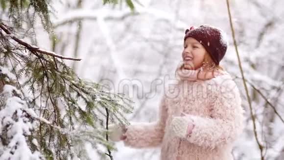 一个穿着粉红色毛皮外套的漂亮女孩抓住了雪花森林里的雪寒假视频的预览图