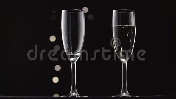 香槟被倒进两个透明的玻璃里博克闪烁的黑色背景视频的预览图