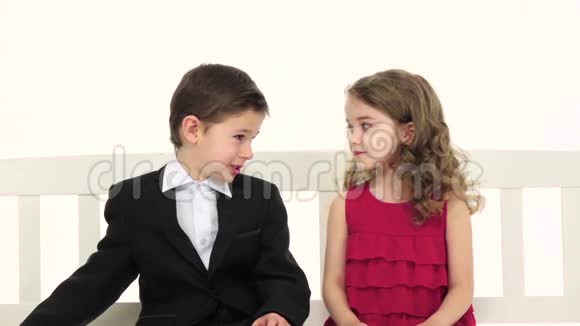 小男孩拿了一条裤子给了女孩一个回报她吻了他的脸颊白色背景慢动作视频的预览图
