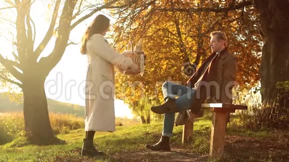 秋天的一对美丽的一对穿着温暖衣服的夫妇站在湖边那里映着秋天的天空褪色了野餐了视频的预览图