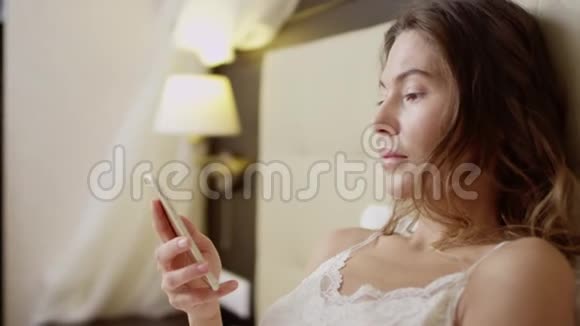 躺在床上的女人拿着一杯香槟和一部智能手机视频的预览图
