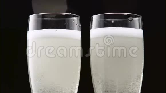 两杯透明的冰镇香槟波克闪烁的黑色背景关门视频的预览图