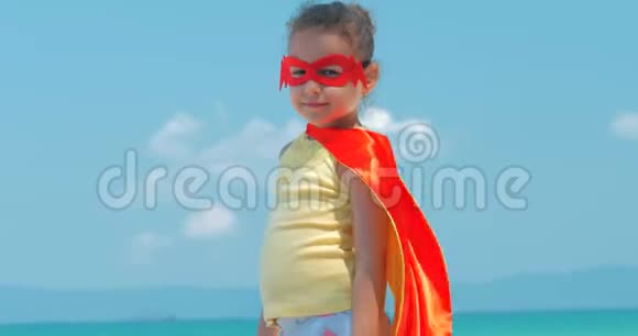穿着超级英雄服装的漂亮小女孩穿着红色斗篷和英雄的面具背景图视频的预览图