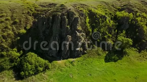 空中镜头飞过风景如画的山谷绿色的田野和山丘岩石悬崖和山脉岩石视频的预览图