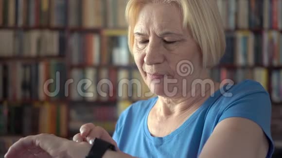 现代高级女性在家使用智能手表口述信息背景书架视频的预览图