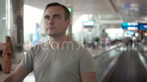 机场航站楼里英俊的年轻人在等飞机使用牵引器环顾四周视频的预览图