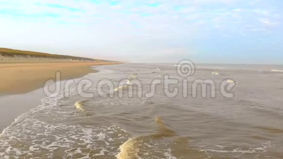 空中观景在阳光明媚的早晨缓慢的运动飞行在海面和海浪中到达海岸荷兰视频的预览图