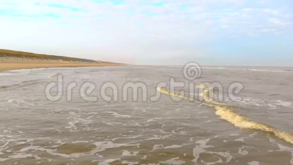 空中观景在阳光明媚的早晨缓慢的运动飞行在海面和海浪中到达海岸荷兰视频的预览图