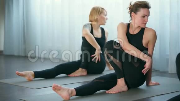 做瑜伽的女性在向帕奇莫塔纳萨纳过渡的过程中进行扭转动作视频的预览图