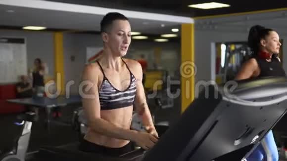 一个女运动员正在跑步机上紧张地跑步在健身俱乐部里用手视频的预览图
