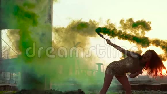 美丽的黑发女郎穿着裙子在缓慢的动作中与绿色的烟雾跳舞视频的预览图