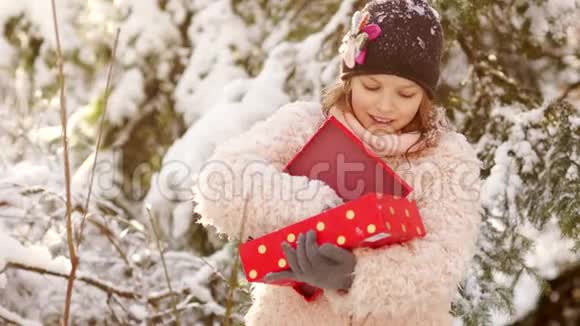 雪林背景下带礼物的女孩她把雪从盒子里扔了出来圣诞节和新年视频的预览图