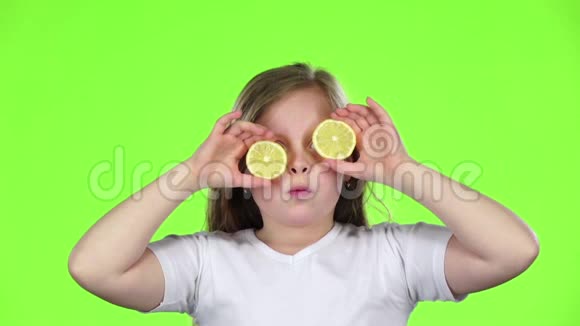 小女孩用柠檬闭上眼睛表现出不同的情绪舔它和呱呱叫绿色屏幕慢动作视频的预览图