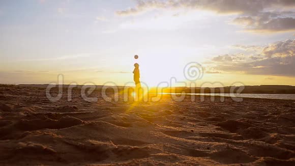 男孩在阳光下用头在海滩上击球在夏天的晚上用沙子训练人视频的预览图