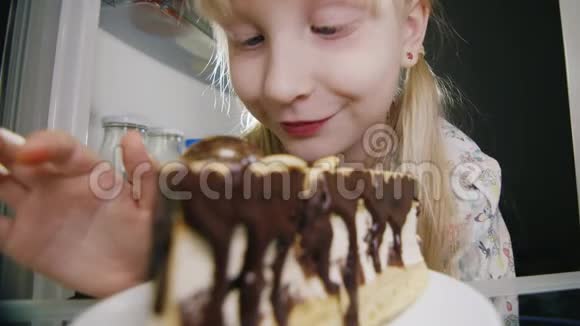 一个小女孩偷偷地尝了尝冰箱里的蛋糕童年的恶作剧快乐的童年视频的预览图
