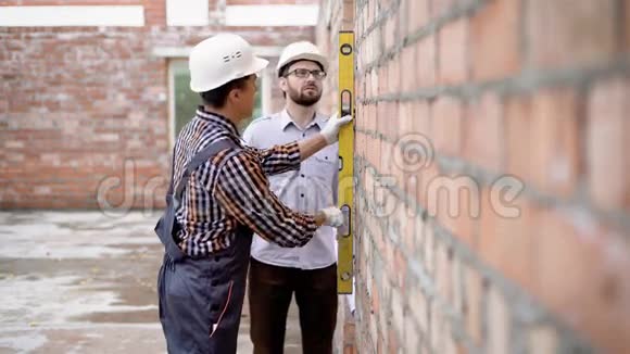 两名男子穿着统一的测量墙在现场配备仪器视频的预览图