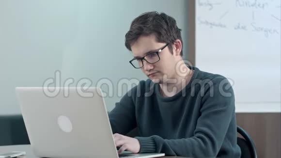 疲倦的学生思考他的工作和使用笔记本电脑视频的预览图