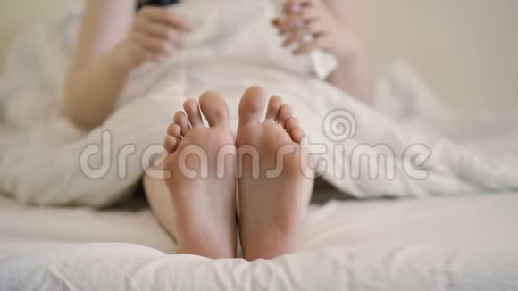 女健康女孩坐在家里的沙发上在受伤的脚踝上涂药膏视频的预览图