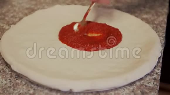 厨师铺番茄酱披萨面团视频的预览图