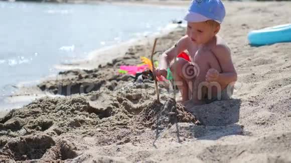 一个孩子在阳光明媚的热天在海滩上玩沙子和玩具娱乐和户外游戏视频的预览图