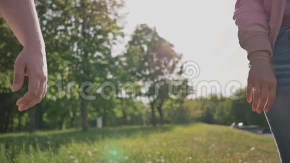 一对浪漫的情侣在绿色的夏天公园里他们在阳光牵手特写镜头视频的预览图