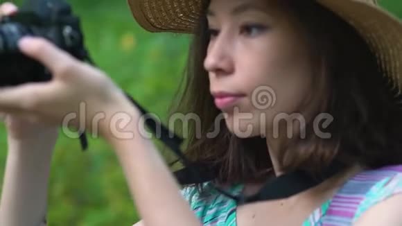 穿着连衣裙和草帽的年轻女子用复古相机拍摄大自然的照片视频的预览图