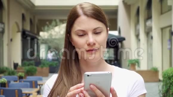 在欧洲城市女人慢吞吞地走在街上女性通过手机与朋友聊天视频的预览图