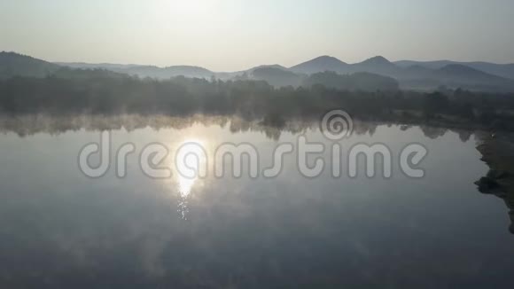 空中飞行穿过晨雾飞越一个山湖山脉中雾状的日出视频的预览图