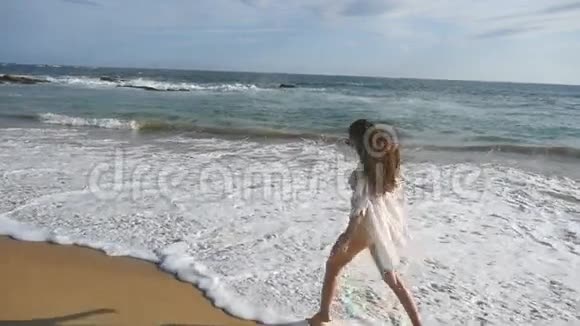 穿比基尼和衬衫的快乐女人在海滩上的海浪中奔跑年轻漂亮的女孩享受生活视频的预览图