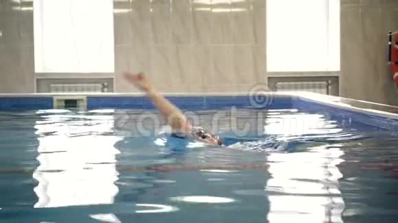 美丽的专业游泳运动员在游泳池里仰泳镜头拍摄视频的预览图