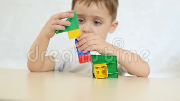 一个孩子正在用彩色积木玩耍在白色背景上坐在一张桌子上慢动作儿童和玩具视频的预览图
