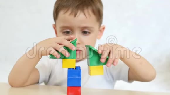 一个孩子正在用彩色积木玩耍慢动作地坐在白色背景上的桌子旁孩子和玩具这就是视频的预览图