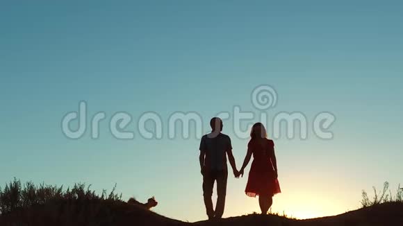 一对情侣的剪影手牵手走向太阳在夕阳下戏剧性的天空背景年轻幸福的一对走视频的预览图