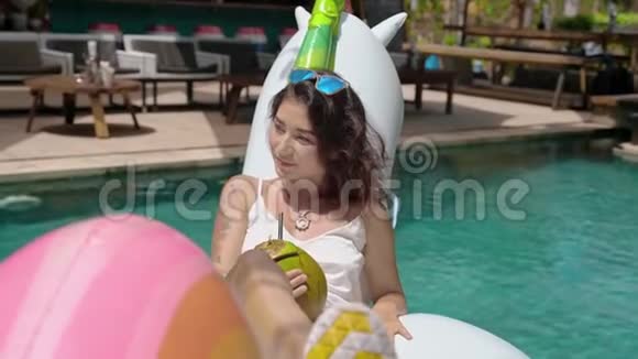 年轻女子在泳池里喝着椰子果视频的预览图