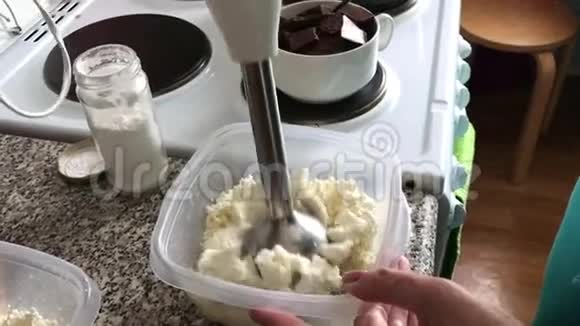 一个女人在容器里用搅拌器研磨干酪甜点的配料视频的预览图