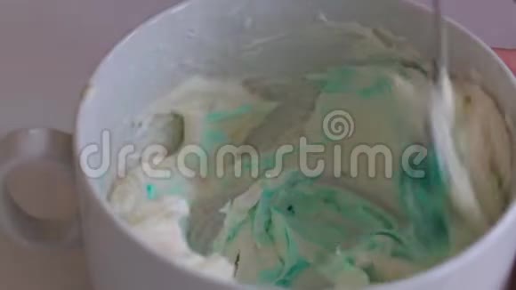 一个女人把奶油奶酪和食用色素混合在一起前给予均匀着色着色奶油以润滑蛋糕视频的预览图