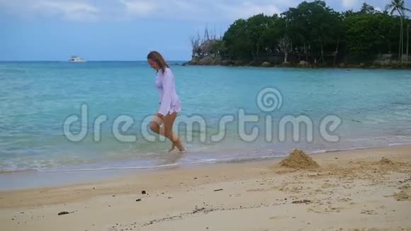一个年轻的女孩沿着海滩岸边奔跑形成了一股浪花视频的预览图