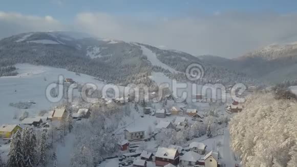 山村在雪中从一个高度日出时飞越喀尔巴阡山的一个村庄空中景观视频的预览图