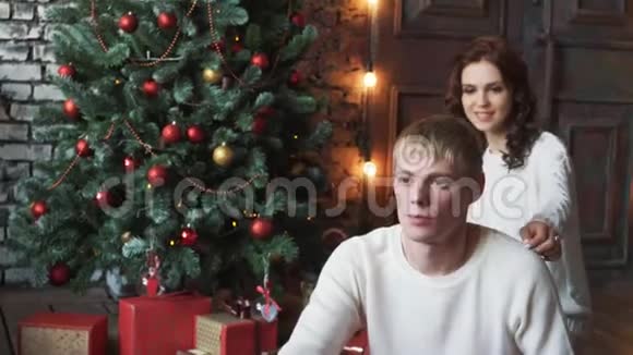 这对年轻夫妇倒在圣诞树上舒适的房子里视频的预览图