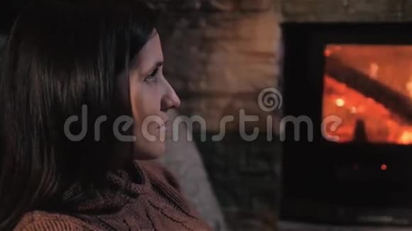 美丽的永布鲁内特女士坐在壁炉旁视频的预览图
