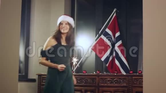 一个女孩模特用手中的火花许愿的肖像圣诞帽圣诞女孩看着摄像机视频的预览图